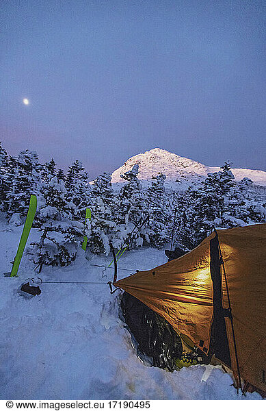 Winter camping with tent in snowy mountains at twilight  New Hampshire