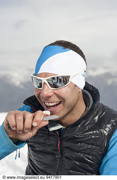 Winter Mann lächeln Sonnenbrille essen essend isst Schnee