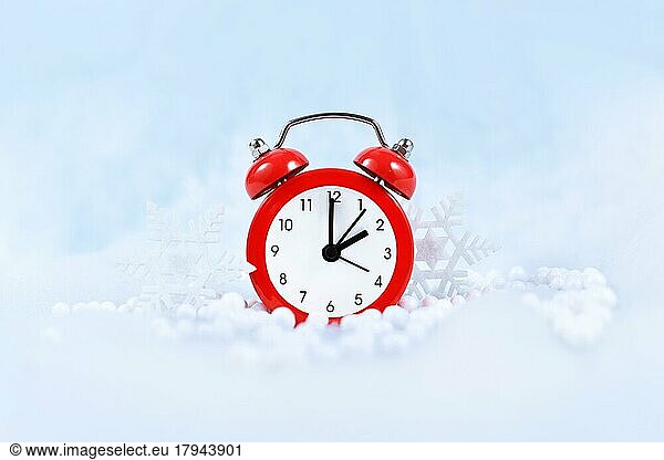 Winter time change for daylight saving in Europe on October 31st concept with red alarm clock between snow