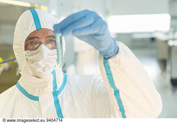 Wissenschaftler im Clean Suit untersucht Probe im Reagenzglas im Labor