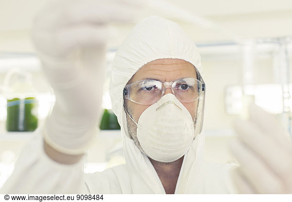 Wissenschaftler im sauberen Anzug mit Pipette und Reagenzglas
