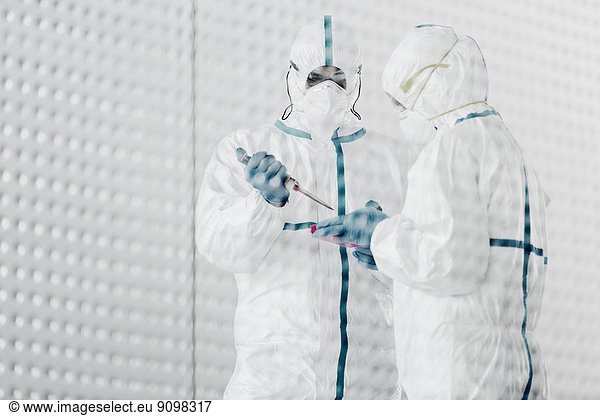Wissenschaftler in sauberen Anzügen  die im Labor arbeiten