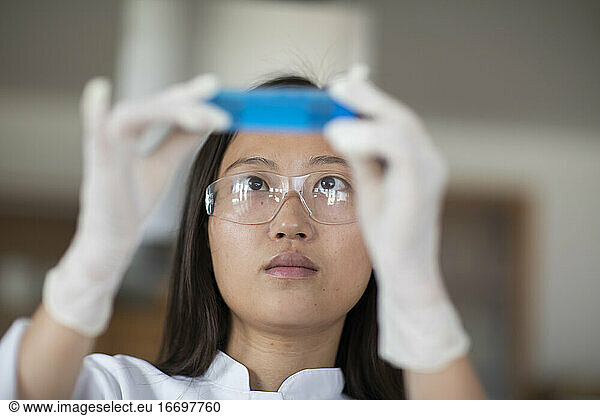 Wissenschaftlerin mit Laborbrille und Röhrchen in einem Labor