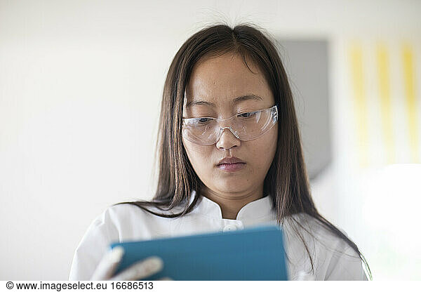 Wissenschaftlerin mit Laborbrille und Tablet in einem Labor