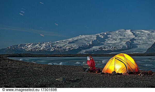 Wissenschaftlerin sitzt im arktischen Klima mit Laptop vor ihrem Zelt