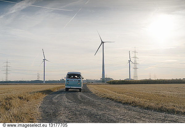 Wohnmobil in ländlicher Landschaft mit Windturbinen bei Sonnenuntergang