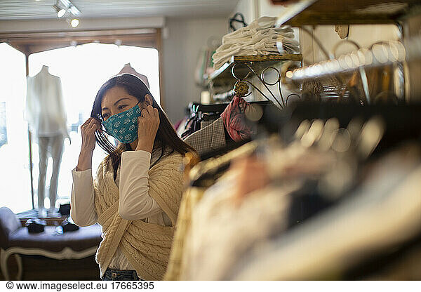 Woman adjusting face mask in clothing boutique