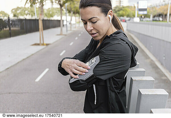 Woman adjusting smart phone on arm band