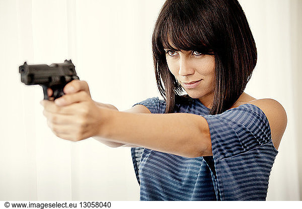 Woman aiming gun while standing home