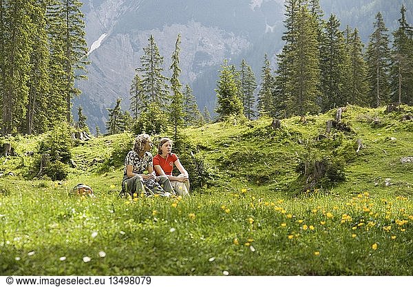 Woman and child sitting in a meadow  Kleiner Ahornboden  Karwendel  Tyrol  Austria  Europe