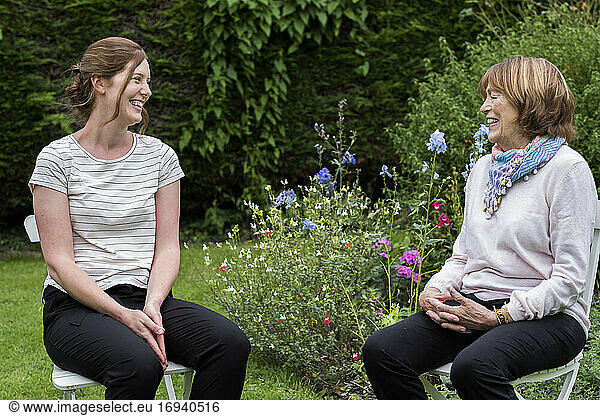 Woman and female therapist seated at an alternative therapy session in a garden.