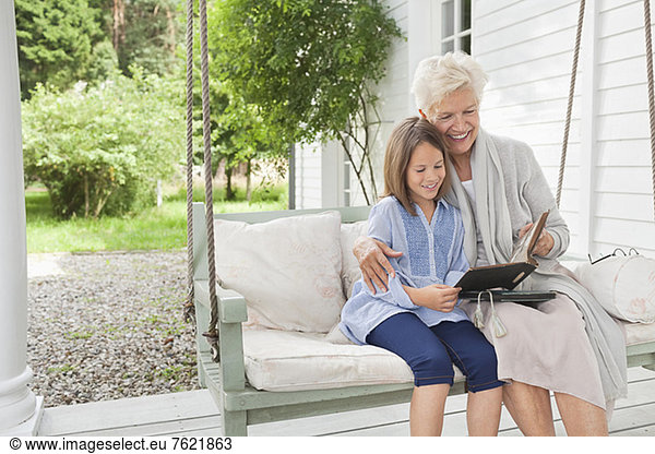 Woman and granddaughter reading on porch swing