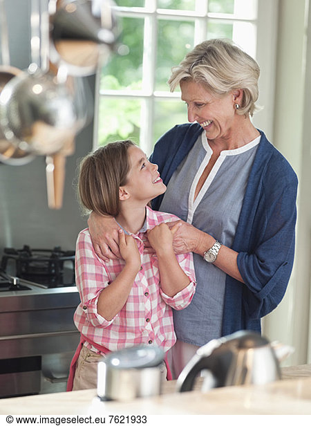 Woman and granddaughter smiling in kitchen