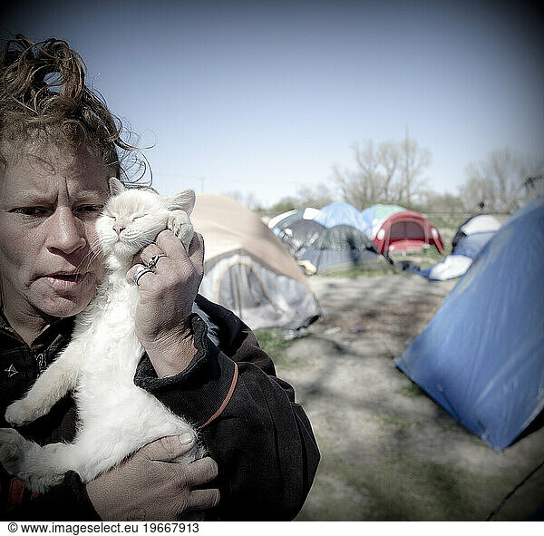 Woman and her cat in a homeless tent city.