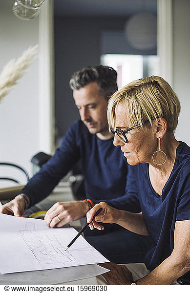 Woman and man discussing blueprint working at home