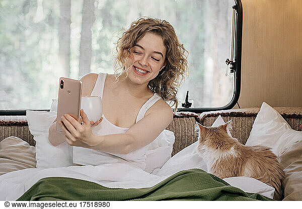 Woman and red ginger cat in trailer with phone.