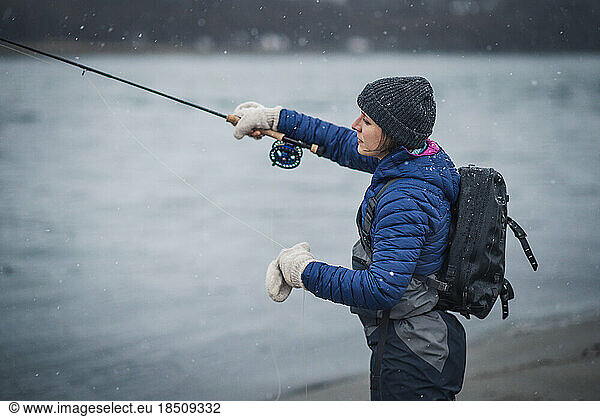 Woman angler casting fly rod in snow storm