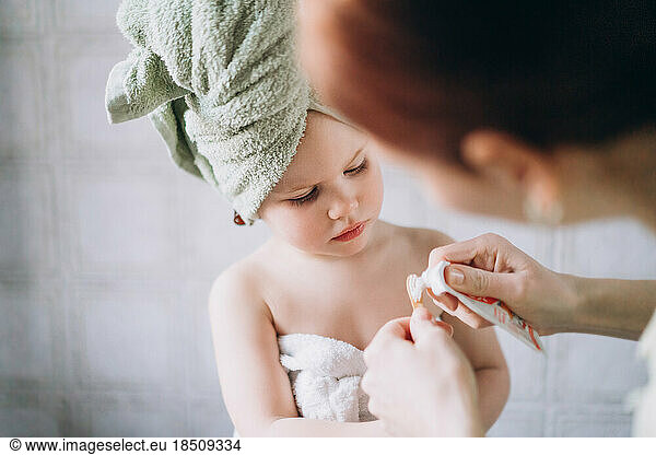 Woman apply toothpaste on children's wooden toothbrush