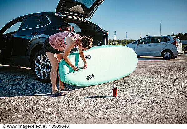 Woman assembling standup paddleboard behind her car
