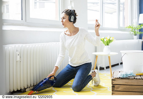 Woman at home wearing headphones hoovering the floor