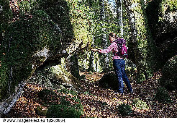 Woman backpacker touching the mossy rocks