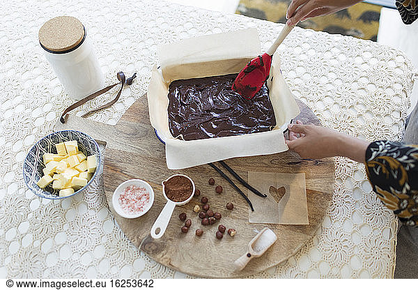 Woman baking chocolate cake at dining table