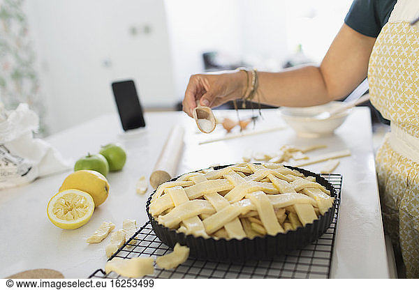 Woman baking fresh homemade lattice apple pie in kitchen