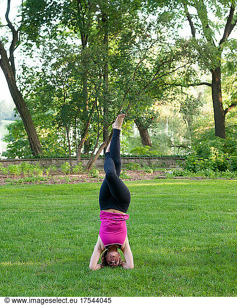 Woman balancing in yoga pose in park.