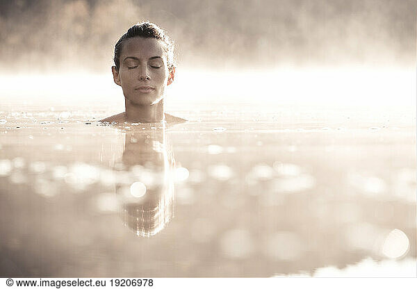 Woman bathing in a lake at morning mist