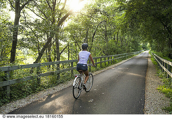 Woman biking through Cape Cod bike path in summer