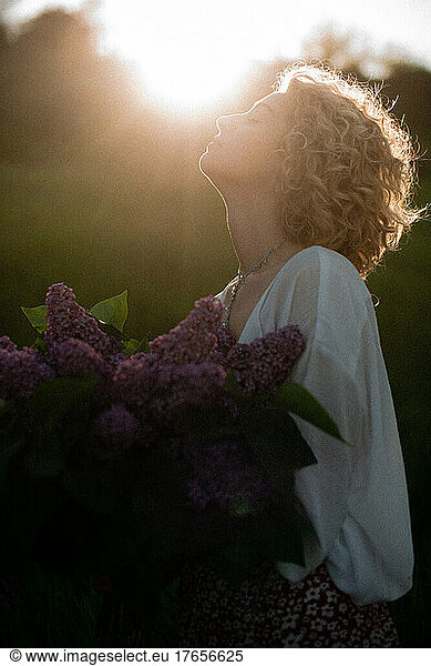 woman blonde with flowers in field sunset