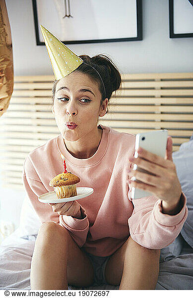 Woman blowing out the candle on the birthday cake and making a selfie