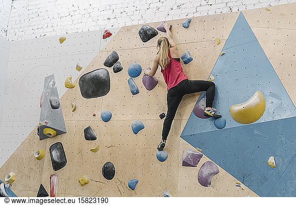 Woman bouldering in climbing gym