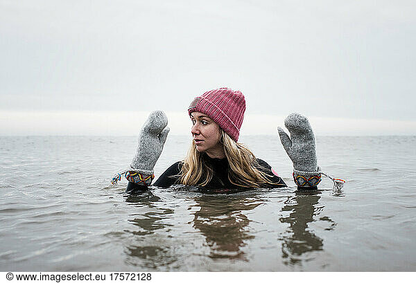 woman breathing cold water swimming with gloves and hat in the ocean