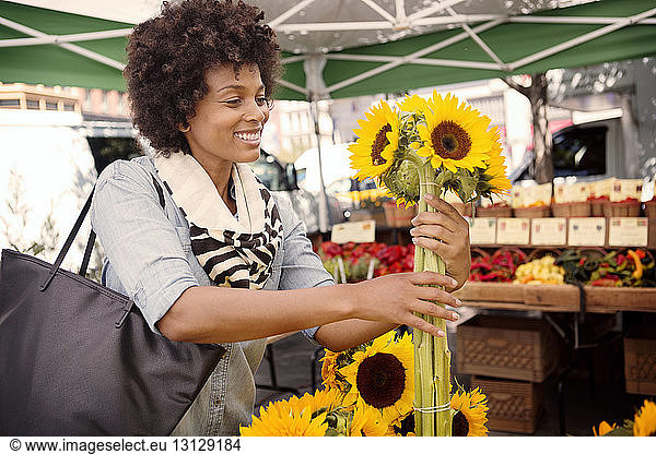 Woman buying sunflowers at market stall