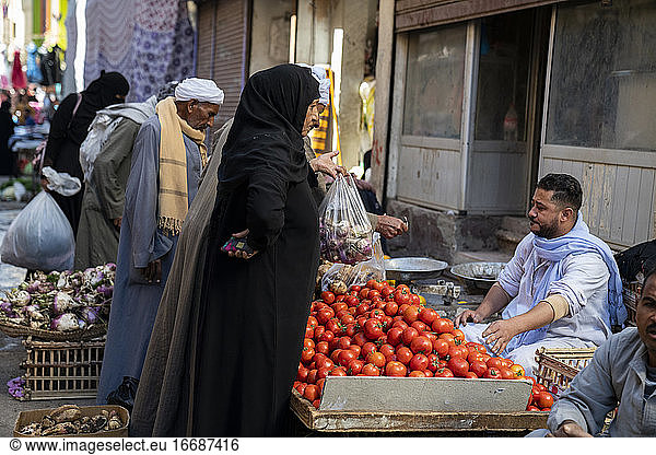 Woman buys tomatoes at an outdoor market