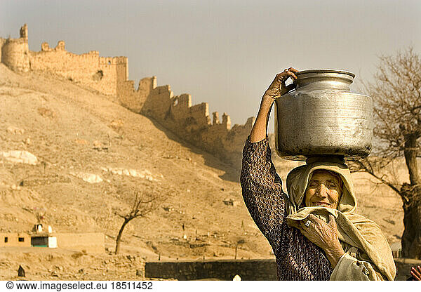 Woman carries large water container on her head after collecting water from well in Kabul  Afghanistan.