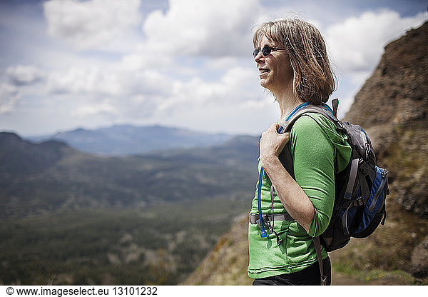 Woman carrying backpack while standing on mountain