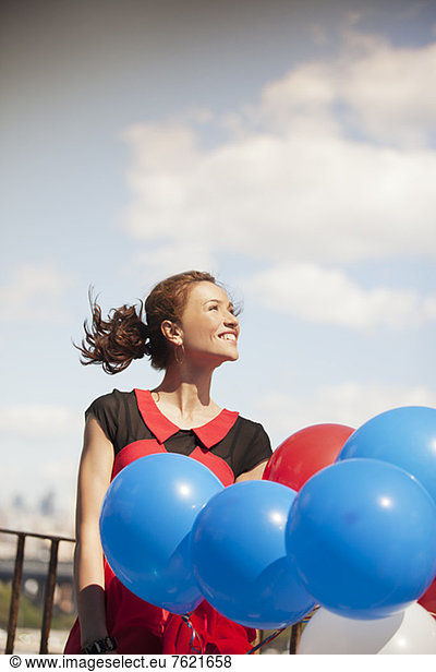 Woman carrying bunch of balloons