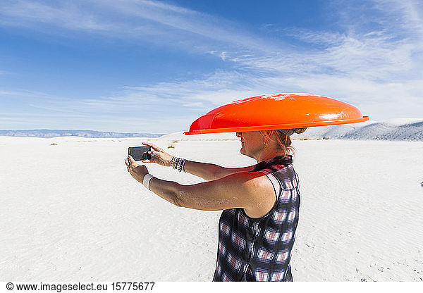 Woman carrying orange sled on her head  taking a selfie