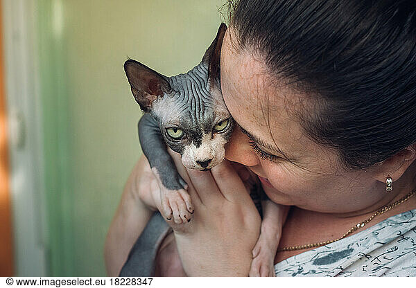 woman carrying Sphynx cat and kisses