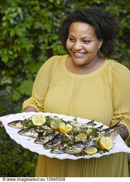 Woman carrying tray of grilled fish