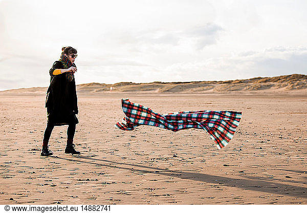 Woman chasing beach blanket