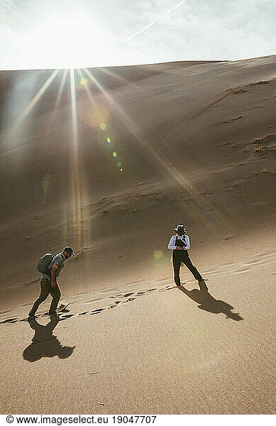 woman checks her phone and waits for male companion hiking in dunes