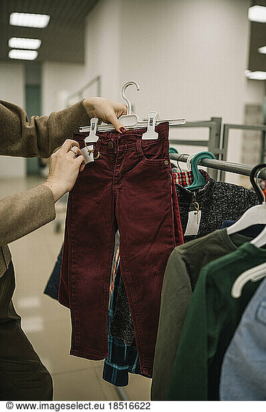 Woman choosing pants from rack in store