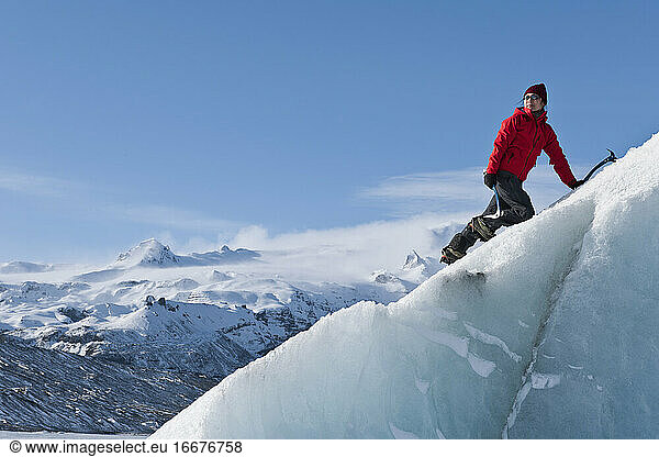 Woman climbinbg iceberg on the Fjallsjoull glacier lagoon