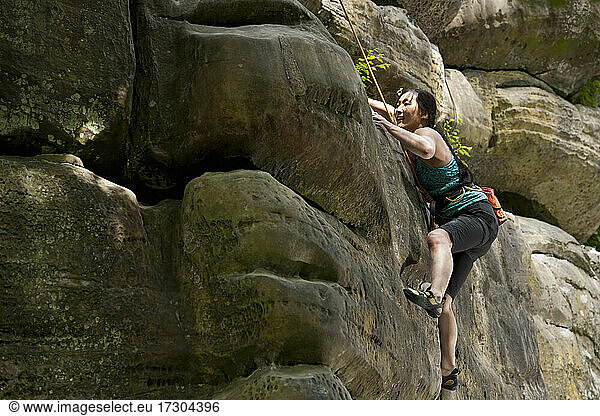 Woman climbing on the sandstone rocks at Harrison's Rock in England