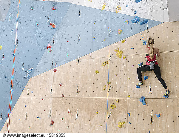 Woman climbing on the wall in climbing gym