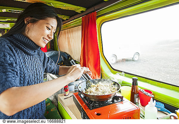 woman cooking inside of camper van at remote location in Iceland