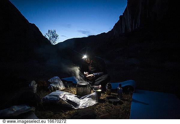 Woman cooks dinner by headlamp on Escalante River  Utah
